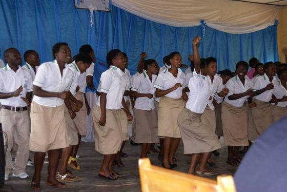 Schülerinnen und Schüler in Schuluniform tanzen auf einer Bühne