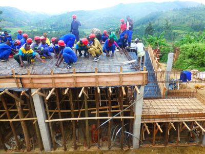 Viele Arbeiter mit Helmen betonieren die Decke