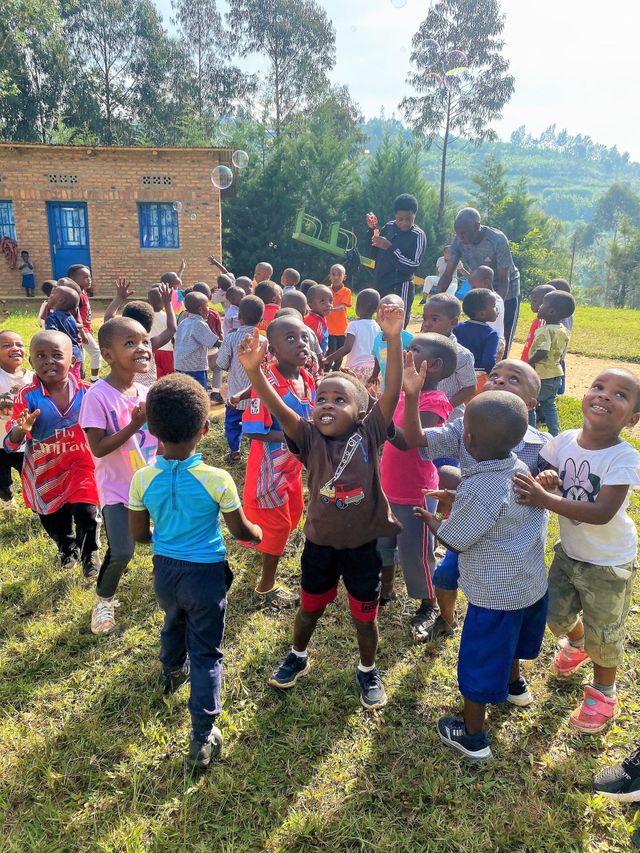 Kindergartenkinder spielen mit Seifenblasen vor dem Kindergarten in Kirinda