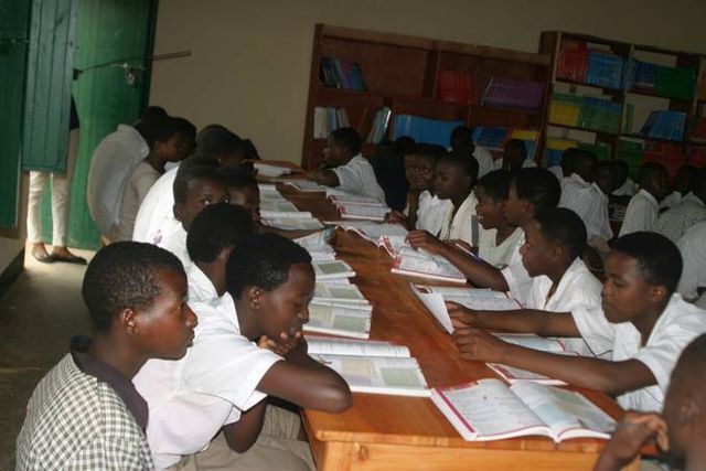 Schülerinnen und Schüler in weißen Hemden lesen an einem langen Tisch in der Bücherei