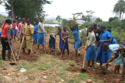 Schülerinnen und Schüler in Uniform arbeiten mit Hacken auf einem Feld
